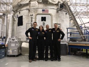 group of four in uniforms posing outside shuttle